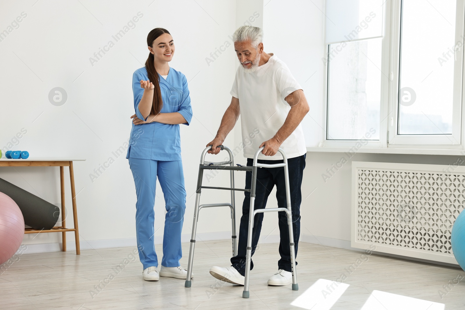 Photo of Nurse talking to senior man with walking frame in clinic