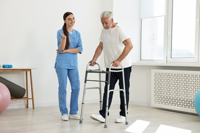 Nurse talking to senior man with walking frame in clinic