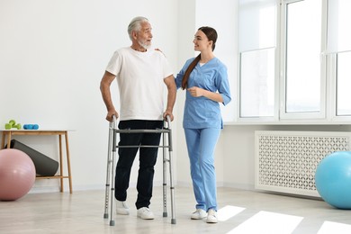 Photo of Nurse helping senior man with walking frame in clinic