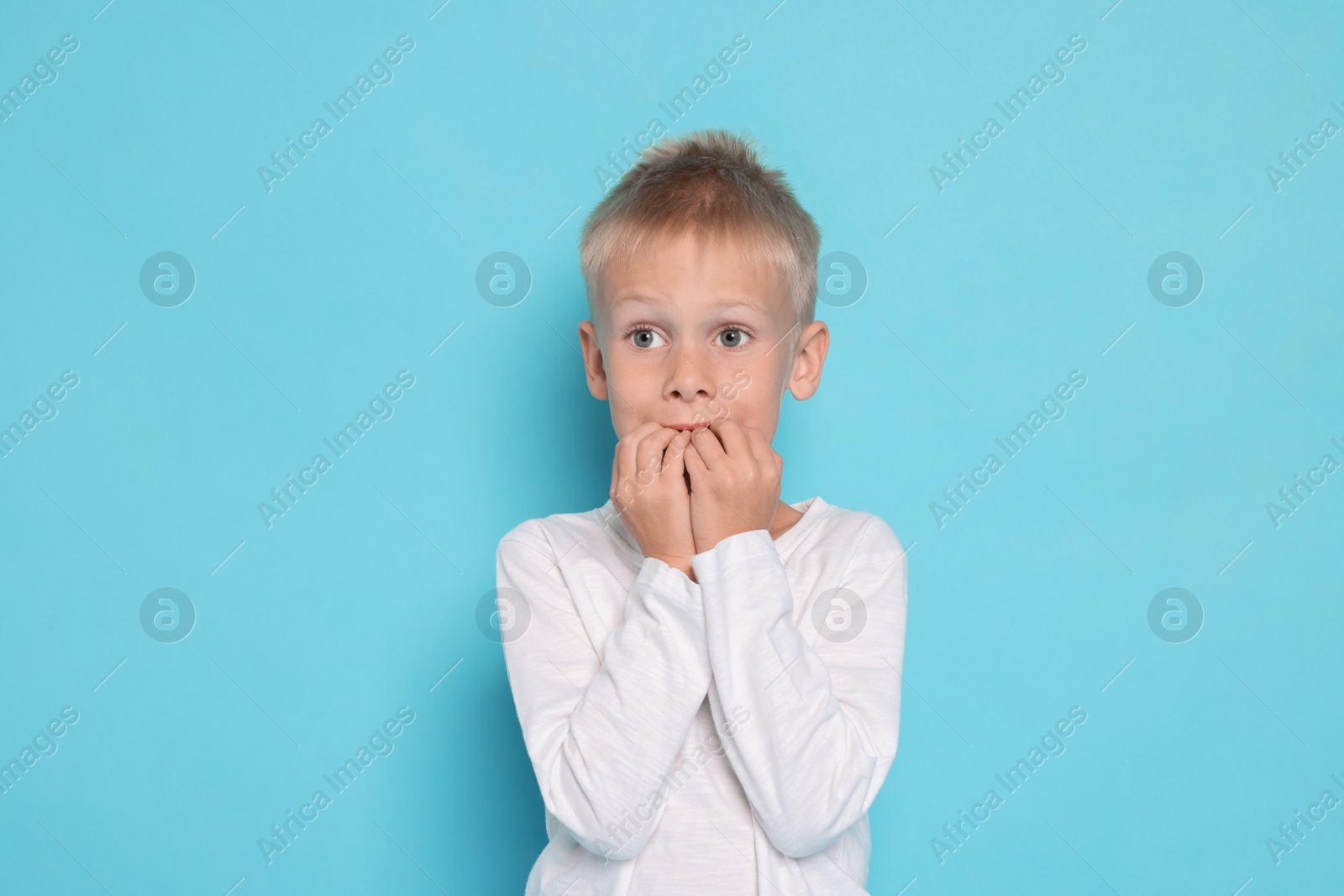 Photo of Scared little boy on light blue background