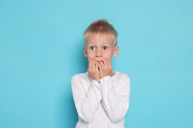 Photo of Scared little boy on light blue background