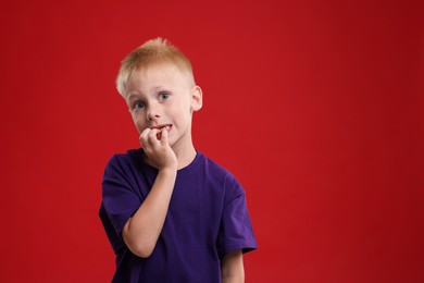 Photo of Scared little boy on red background. Space for text