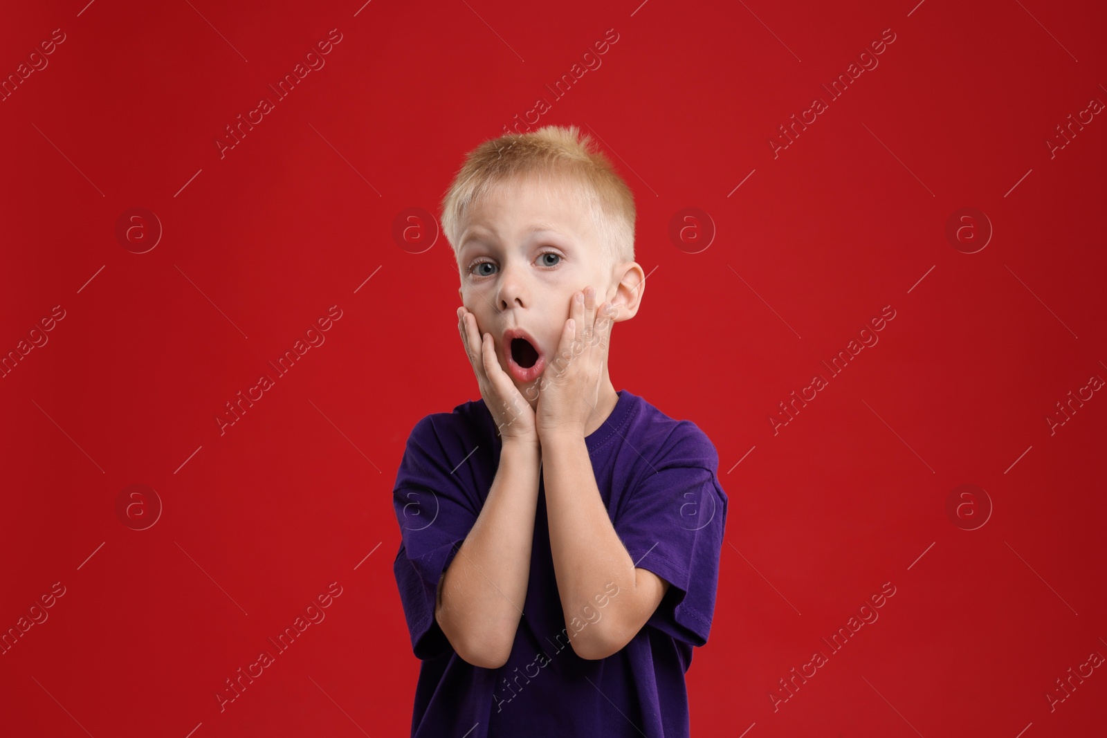 Photo of Portrait of scared little boy on red background