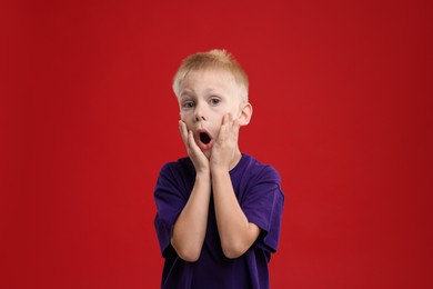 Portrait of scared little boy on red background