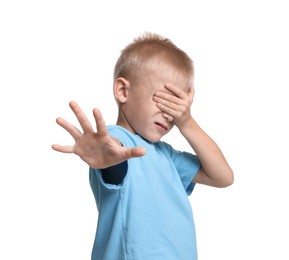 Scared little boy covering eyes on white background