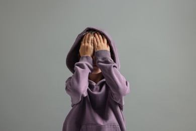 Photo of Scared little boy covering face with hands on grey background