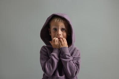 Portrait of scared little boy on grey background