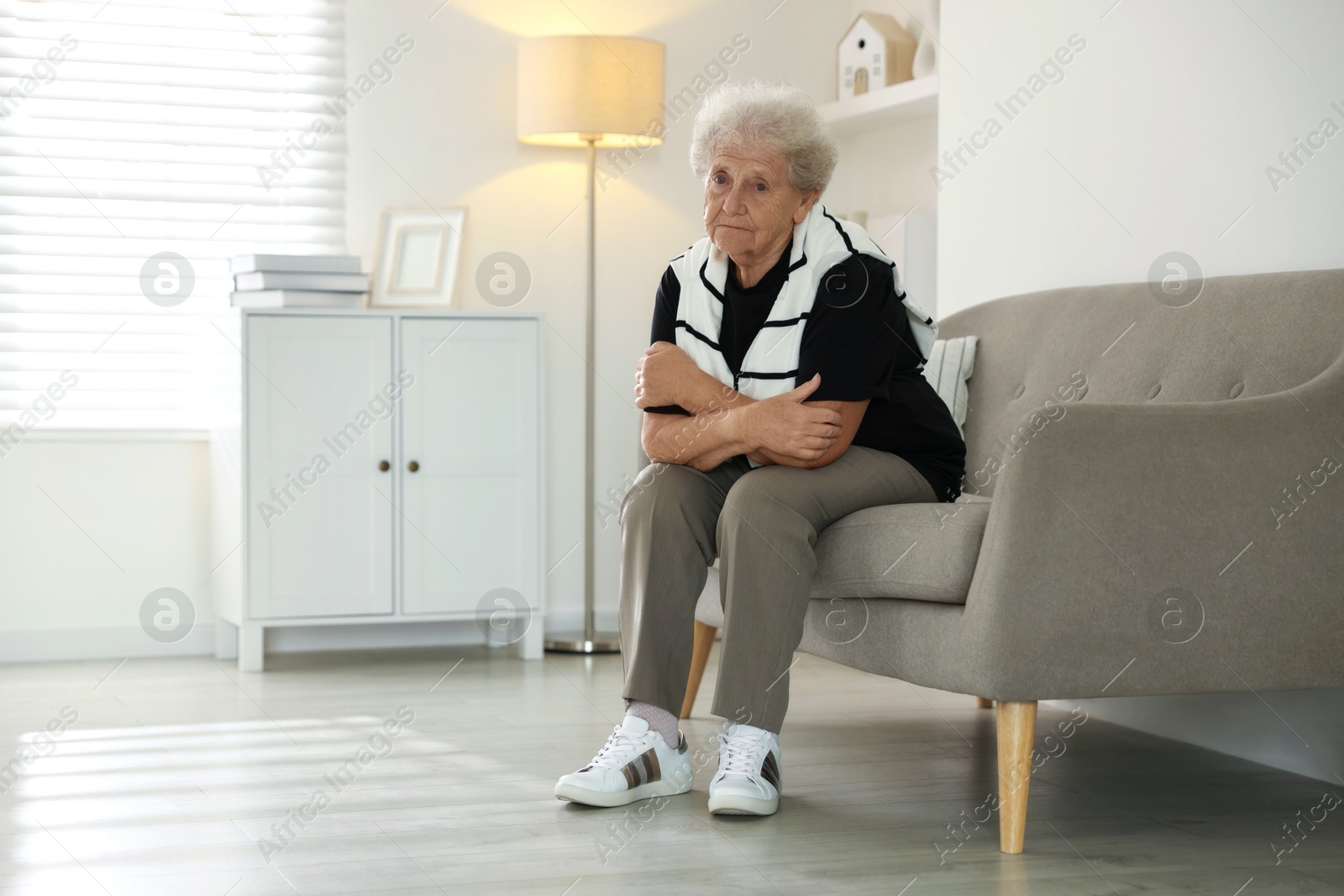 Photo of Loneliness concept. Sad senior woman sitting on sofa at home