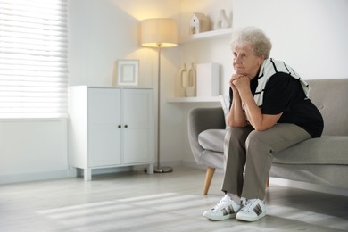 Photo of Loneliness concept. Sad senior woman sitting on sofa at home