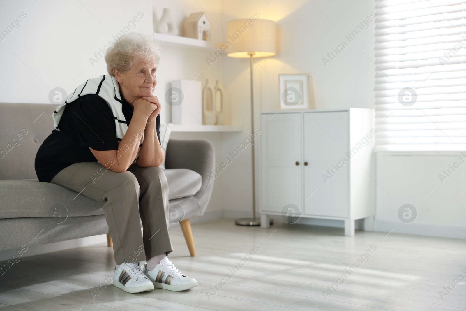 Photo of Loneliness concept. Sad senior woman sitting on sofa at home