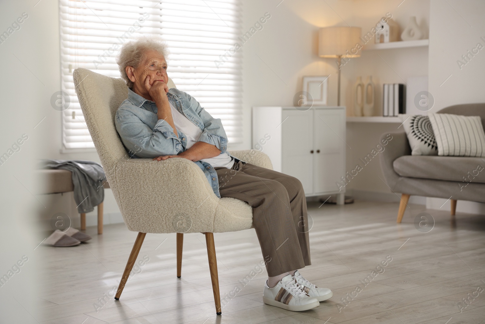 Photo of Loneliness concept. Sad senior woman sitting in armchair at home