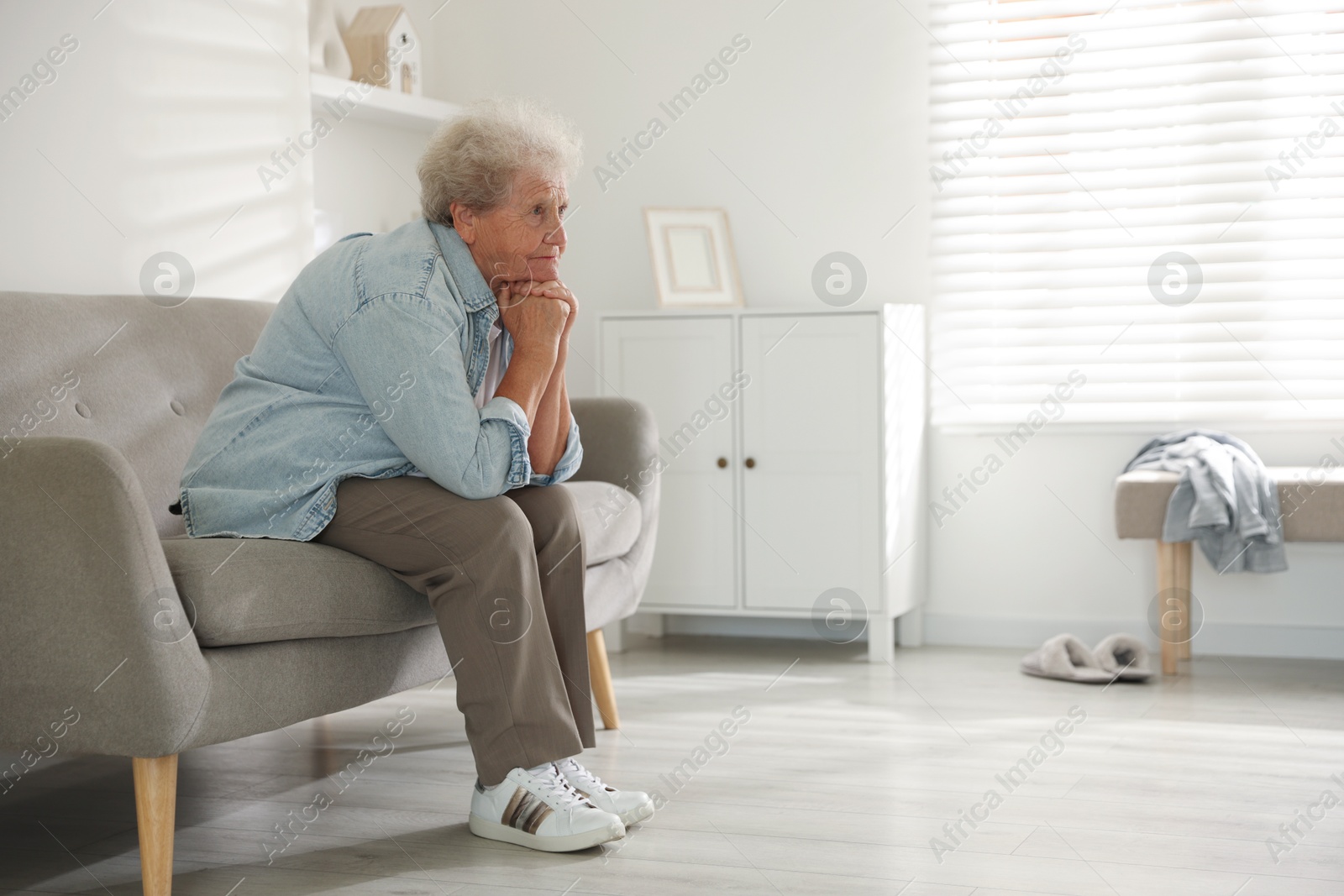 Photo of Loneliness concept. Sad senior woman sitting on sofa at home