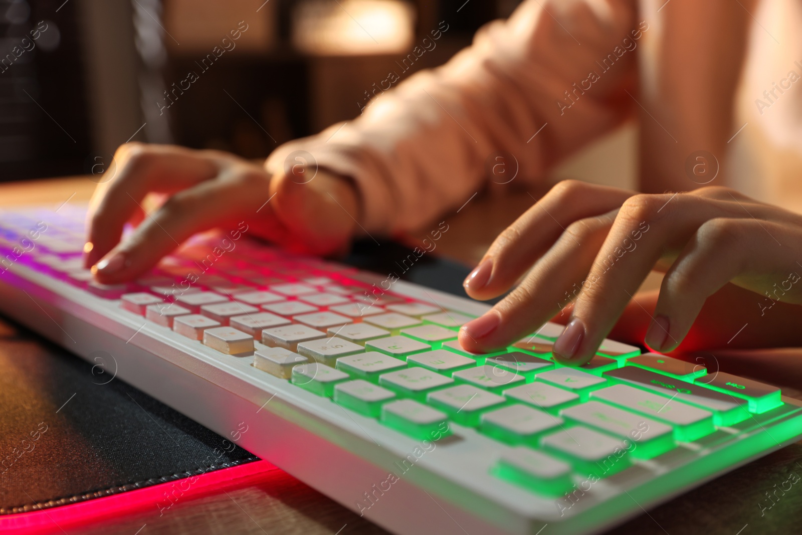 Photo of Girl using computer keyboard at wooden table indoors, closeup