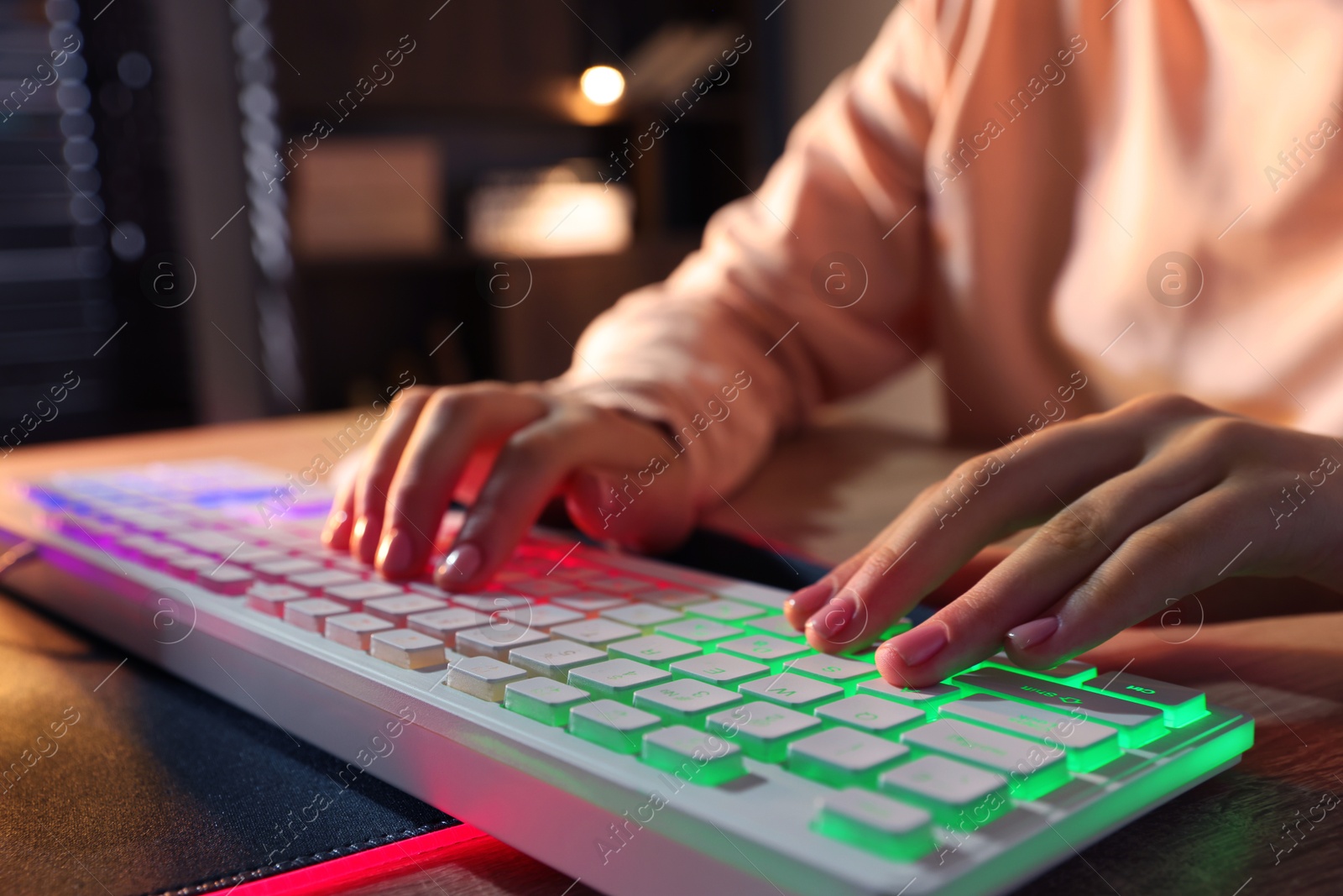 Photo of Girl using computer keyboard at wooden table indoors, closeup