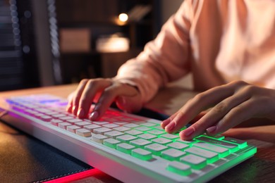 Photo of Girl using computer keyboard at wooden table indoors, closeup