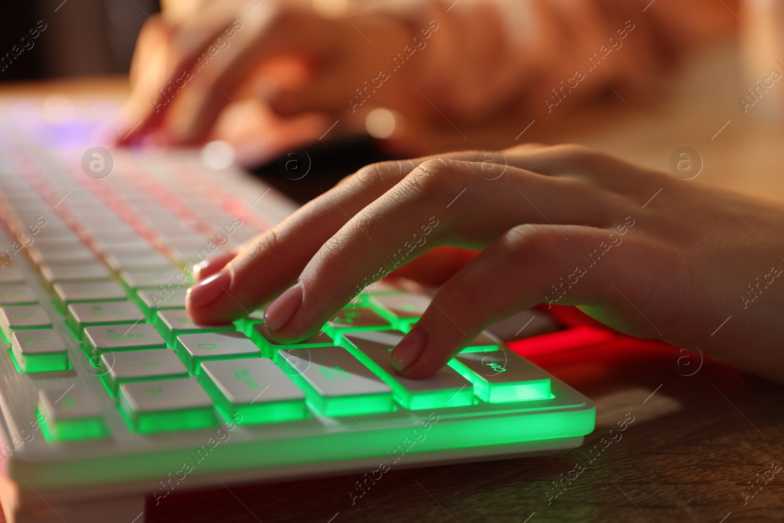 Photo of Girl using computer keyboard at wooden table indoors, closeup