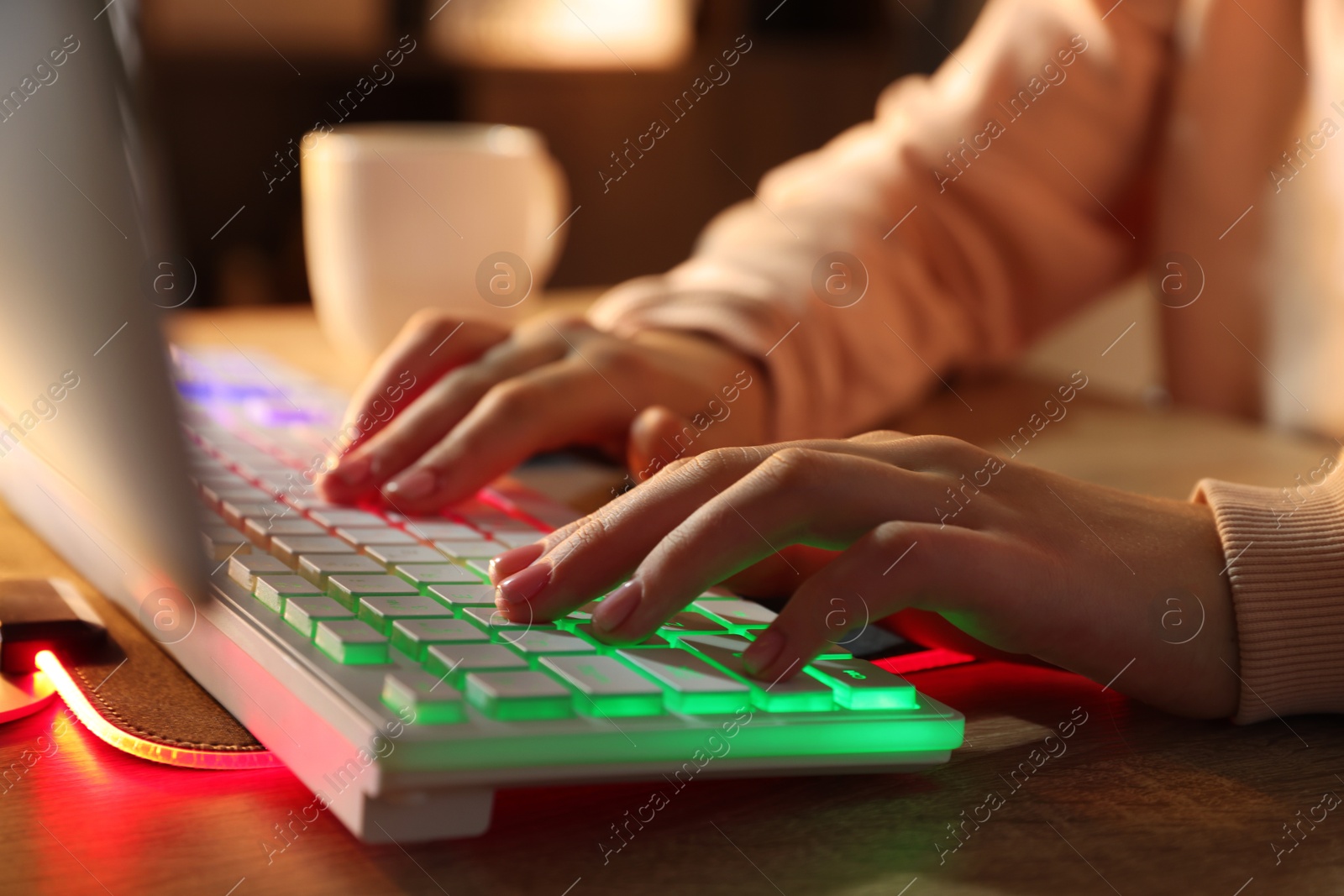 Photo of Girl using computer keyboard at wooden table indoors, closeup