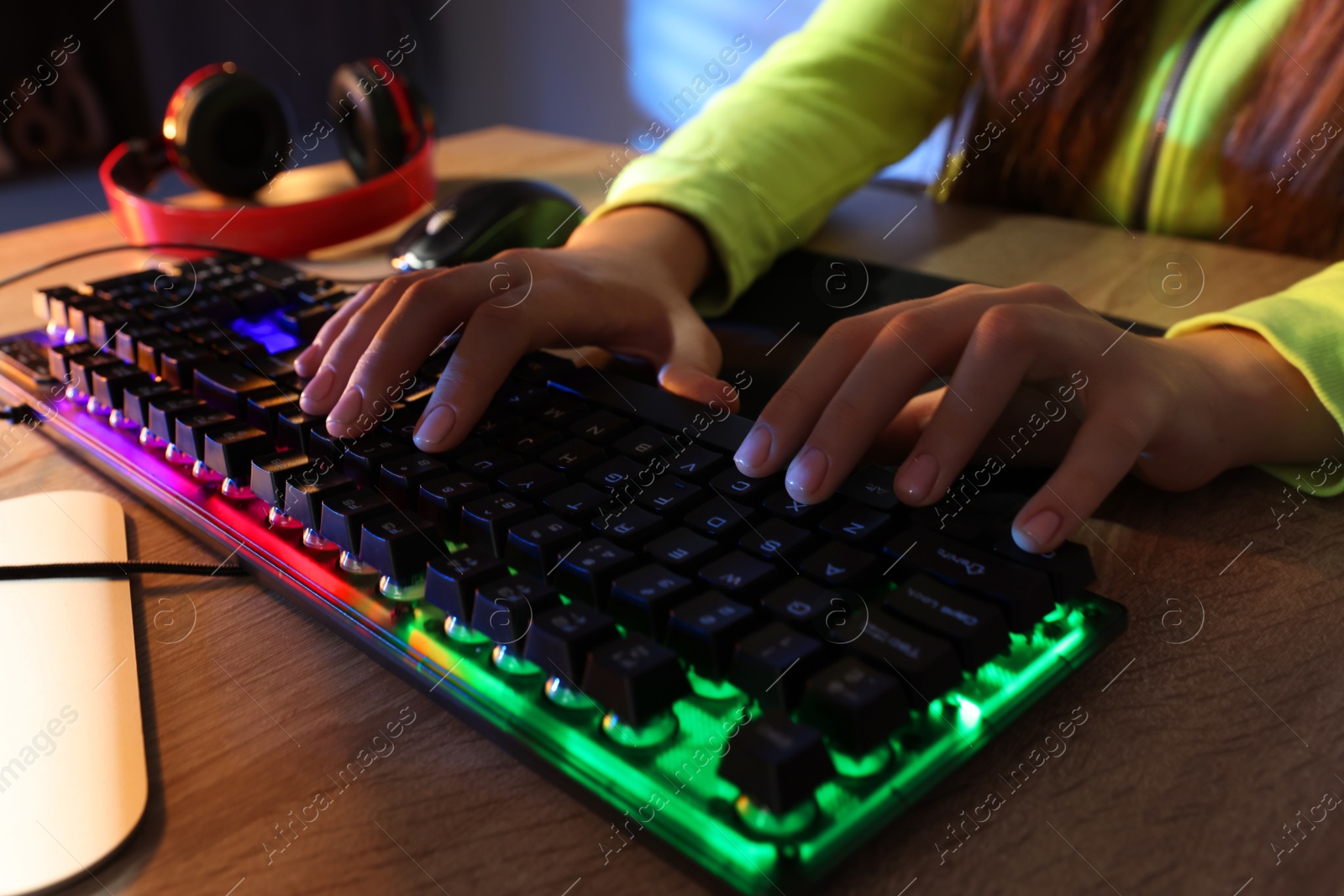 Photo of Girl using computer keyboard at wooden table indoors, closeup