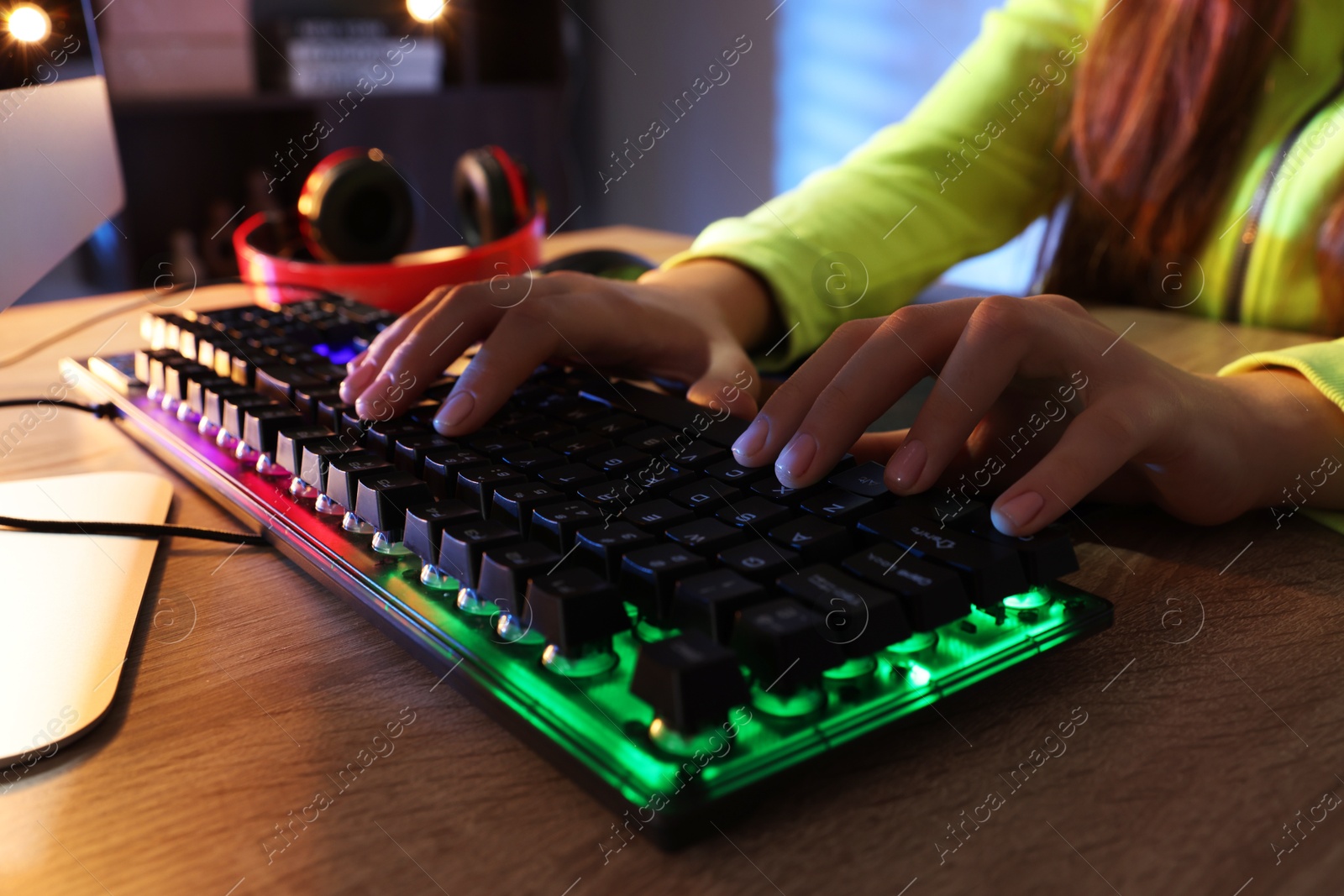 Photo of Girl using computer keyboard at wooden table indoors, closeup