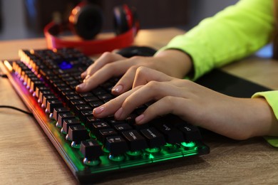 Photo of Girl using computer keyboard at wooden table indoors, closeup