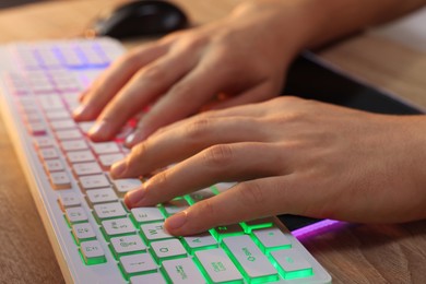 Young man using computer keyboard at wooden table indoors, closeup