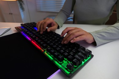 Photo of Woman using computer keyboard at white table indoors, closeup