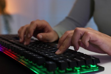 Photo of Woman using computer keyboard at white table indoors, closeup