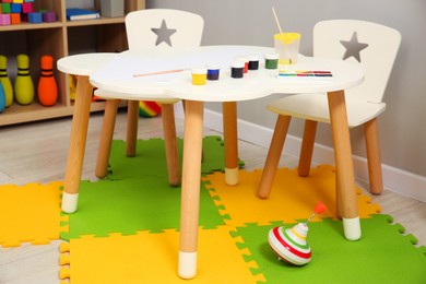 Photo of Beautiful kid's room interior with toys, paints and stylish furniture