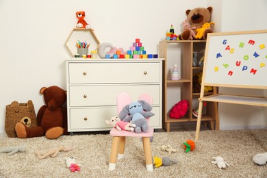 Photo of Beautiful kid's room interior with toys, whiteboard and stylish furniture