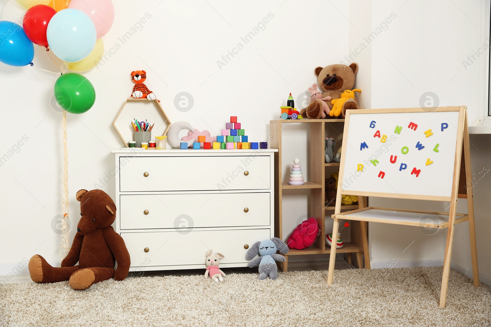 Photo of Beautiful kid's room interior with toys, whiteboard and stylish furniture