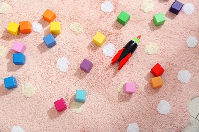 Photo of Colorful cubes and rocket toy in child's room, top view