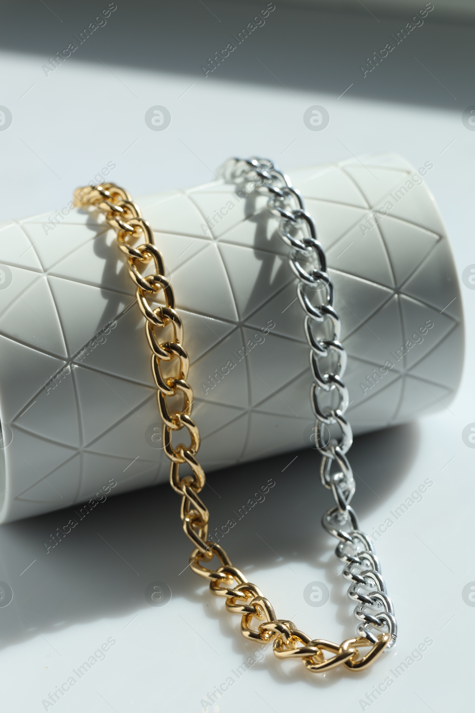 Photo of Metal chain on white table, closeup. Luxury jewelry