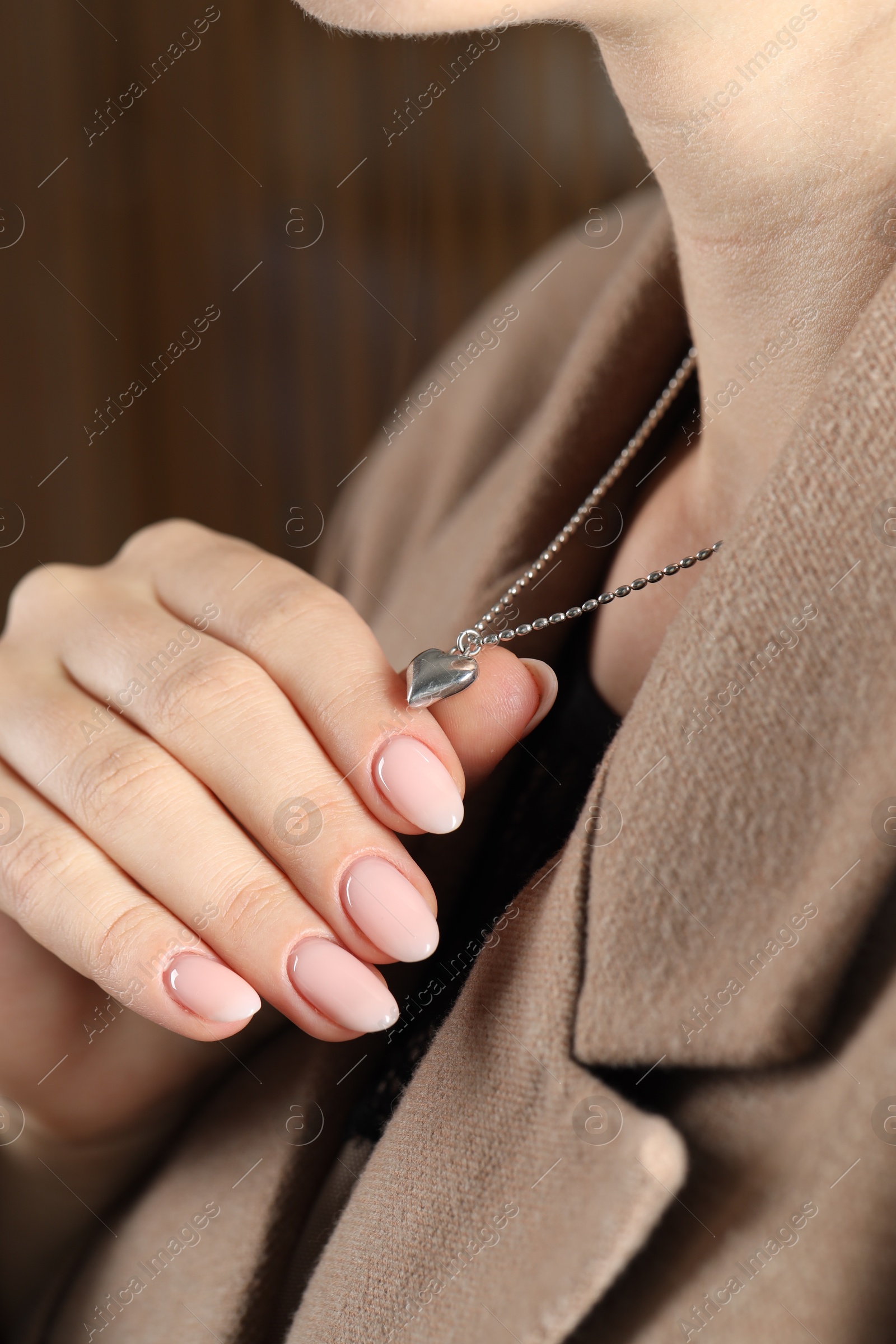 Photo of Woman wearing stylish metal chain with pendant, closeup. Luxury jewelry