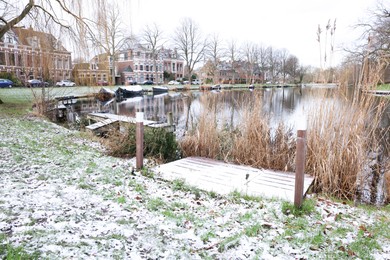 Photo of Picturesque view of water canal with moored boats in city on winter day