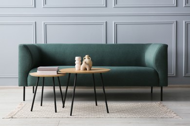 Stylish sofa, books and decor elements on nesting tables in room