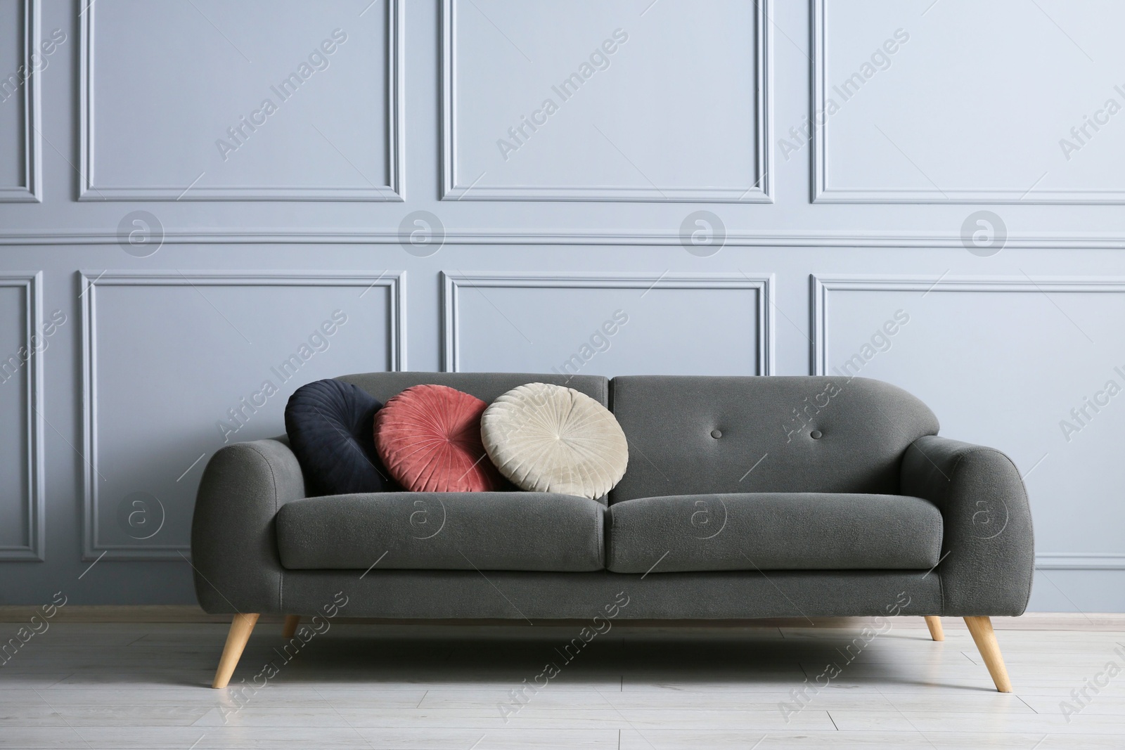 Photo of Stylish sofa with cushions near grey wall