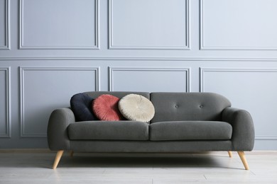 Stylish sofa with cushions near grey wall