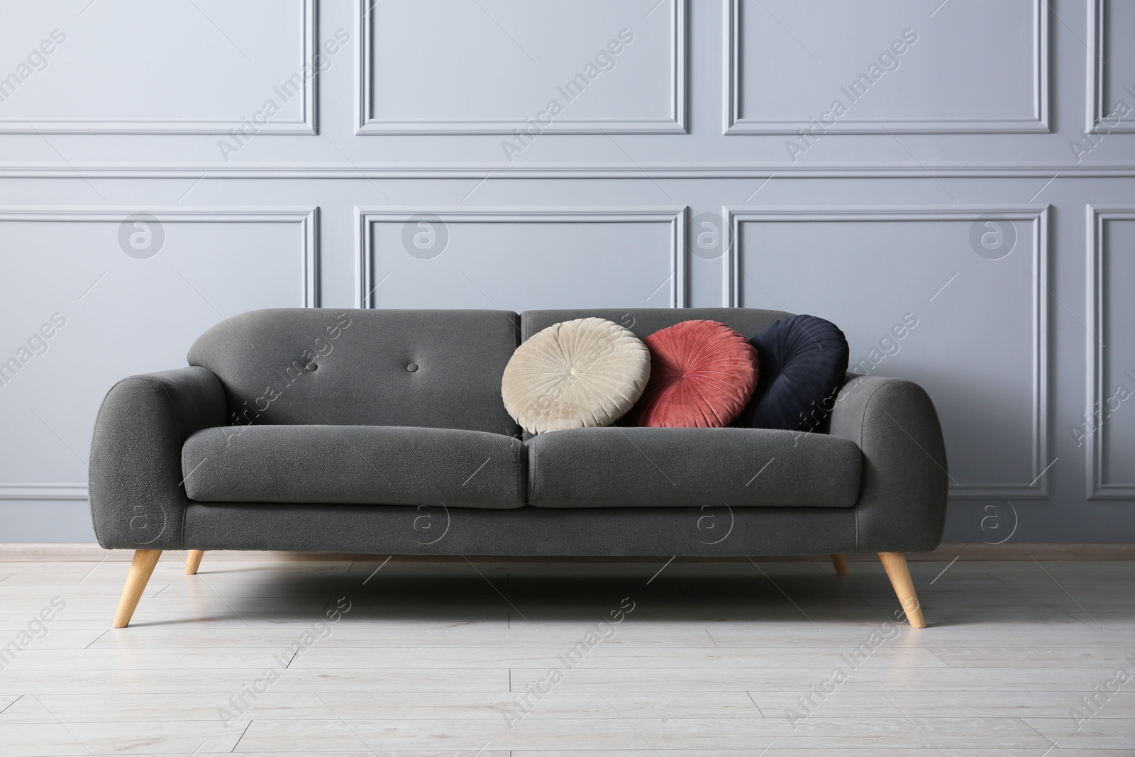 Photo of Stylish sofa with cushions near grey wall