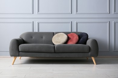 Stylish sofa with cushions near grey wall