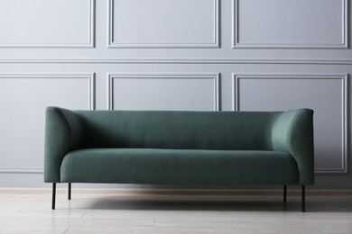 Photo of One stylish sofa near grey wall indoors