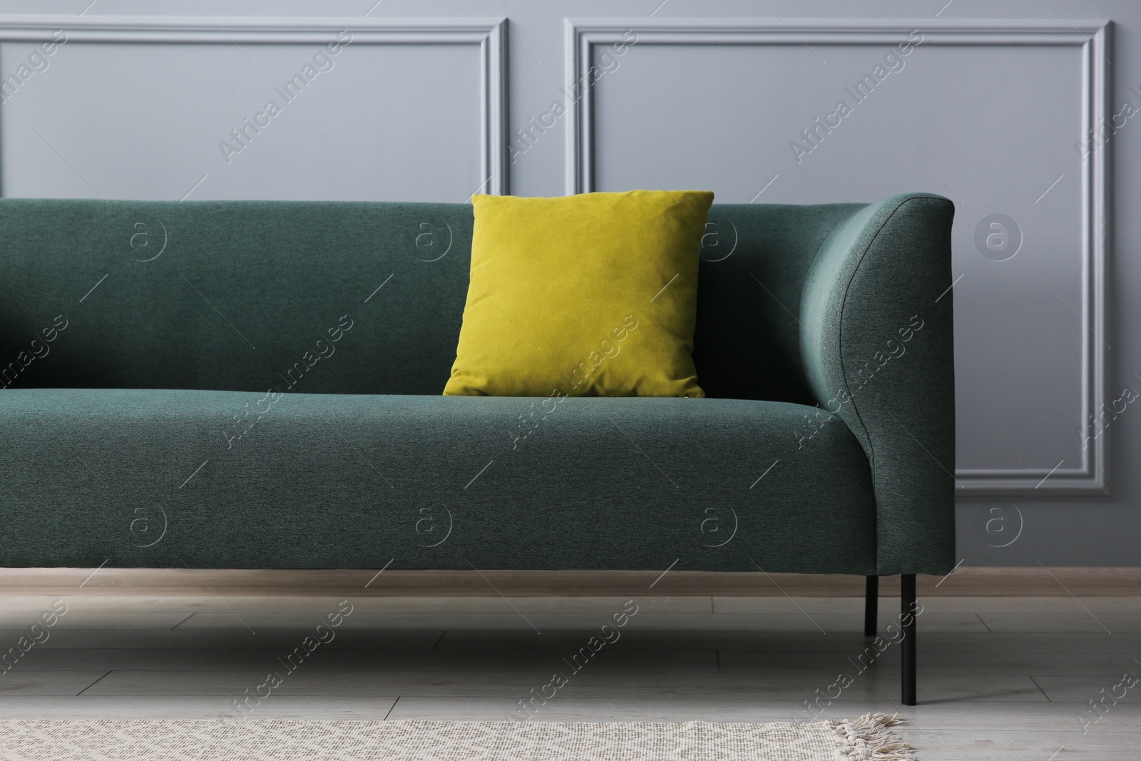 Photo of Stylish sofa with cushion near grey wall