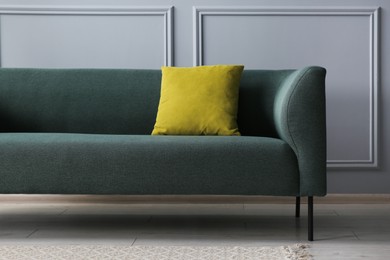 Stylish sofa with cushion near grey wall