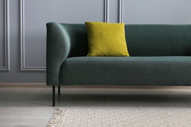 Photo of Stylish sofa with cushion near grey wall