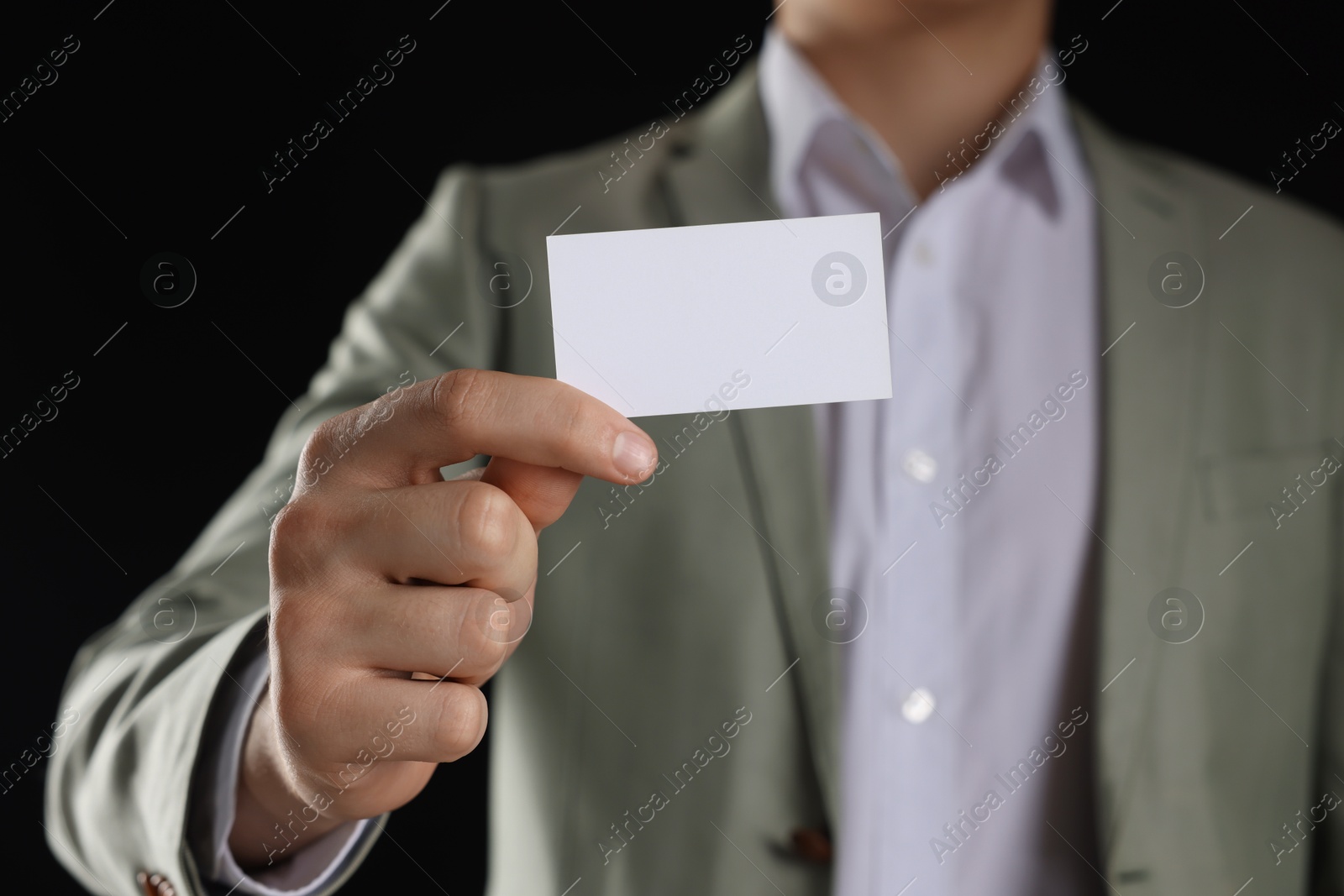 Photo of Man holding blank business card on black background, closeup. Mockup for design