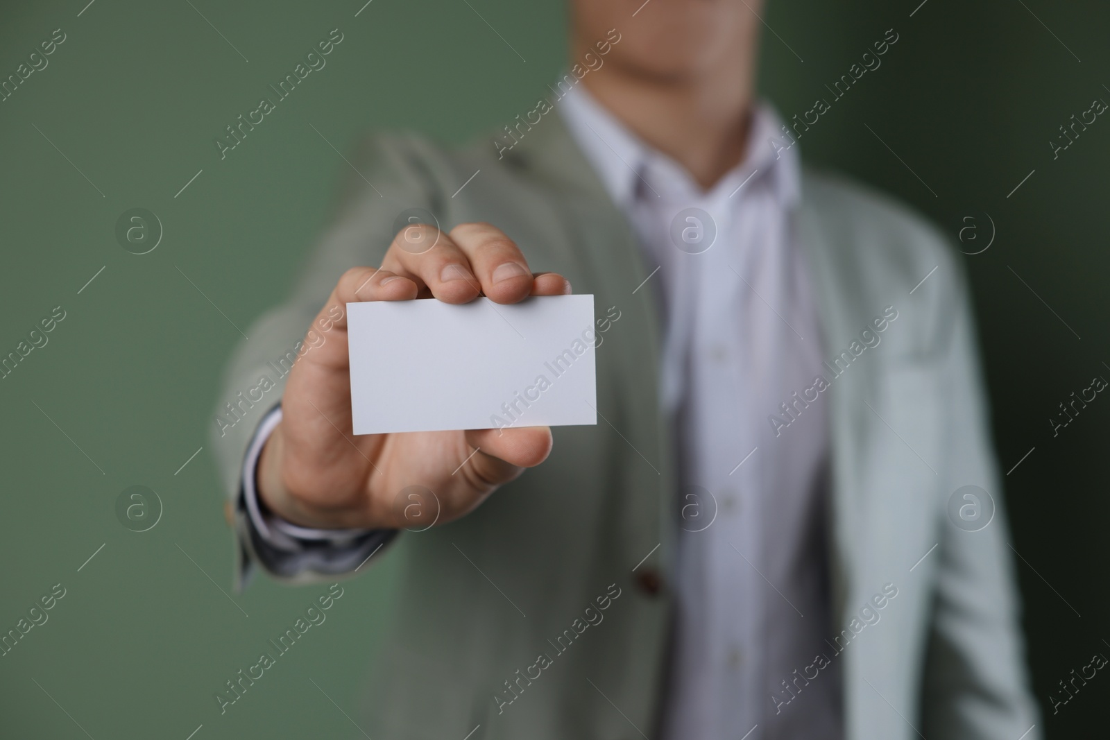 Photo of Man holding blank business card on green background, closeup. Mockup for design