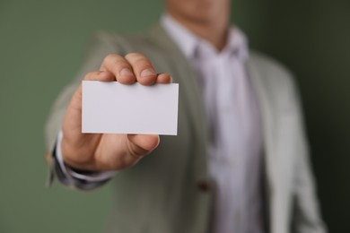 Photo of Man holding blank business card on green background, closeup. Mockup for design