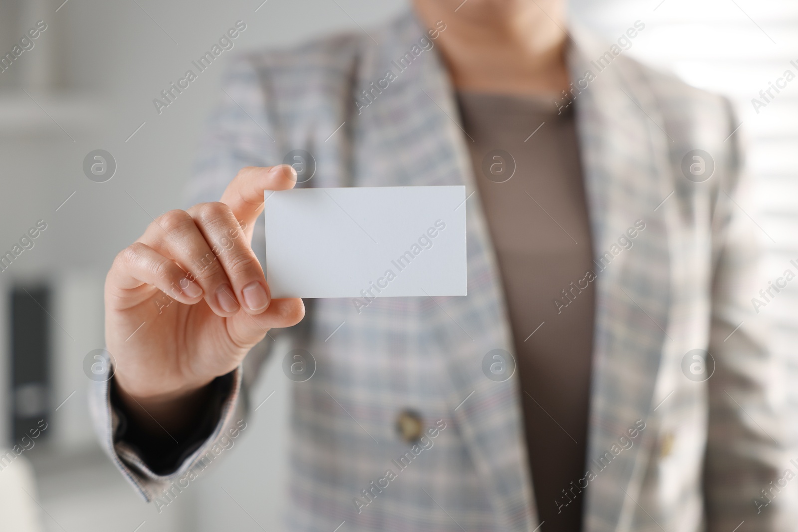 Photo of Woman holding blank business card in office, closeup. Mockup for design