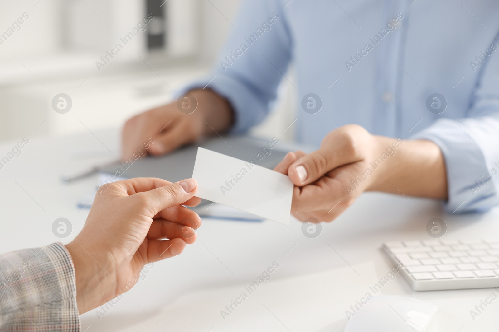 Photo of Man giving business card to woman at table in office, closeup. Mockup for design