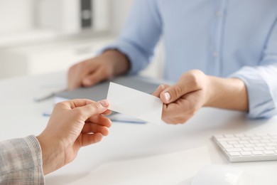 Photo of Man giving business card to woman at table in office, closeup. Mockup for design