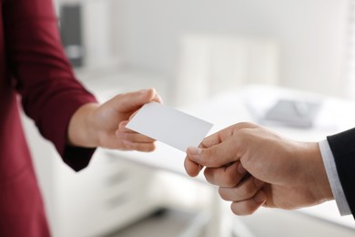 Photo of Woman giving business card to man in office, closeup. Mockup for design